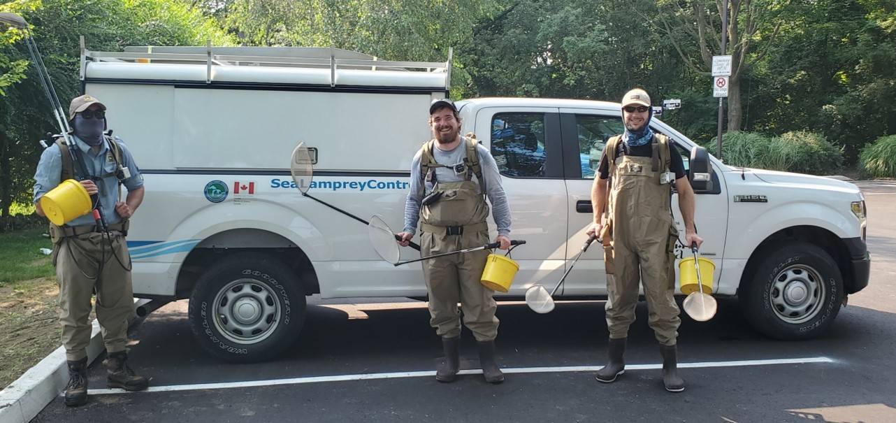 Three people in front of SLCC (DFO) truck with electrofishing gear